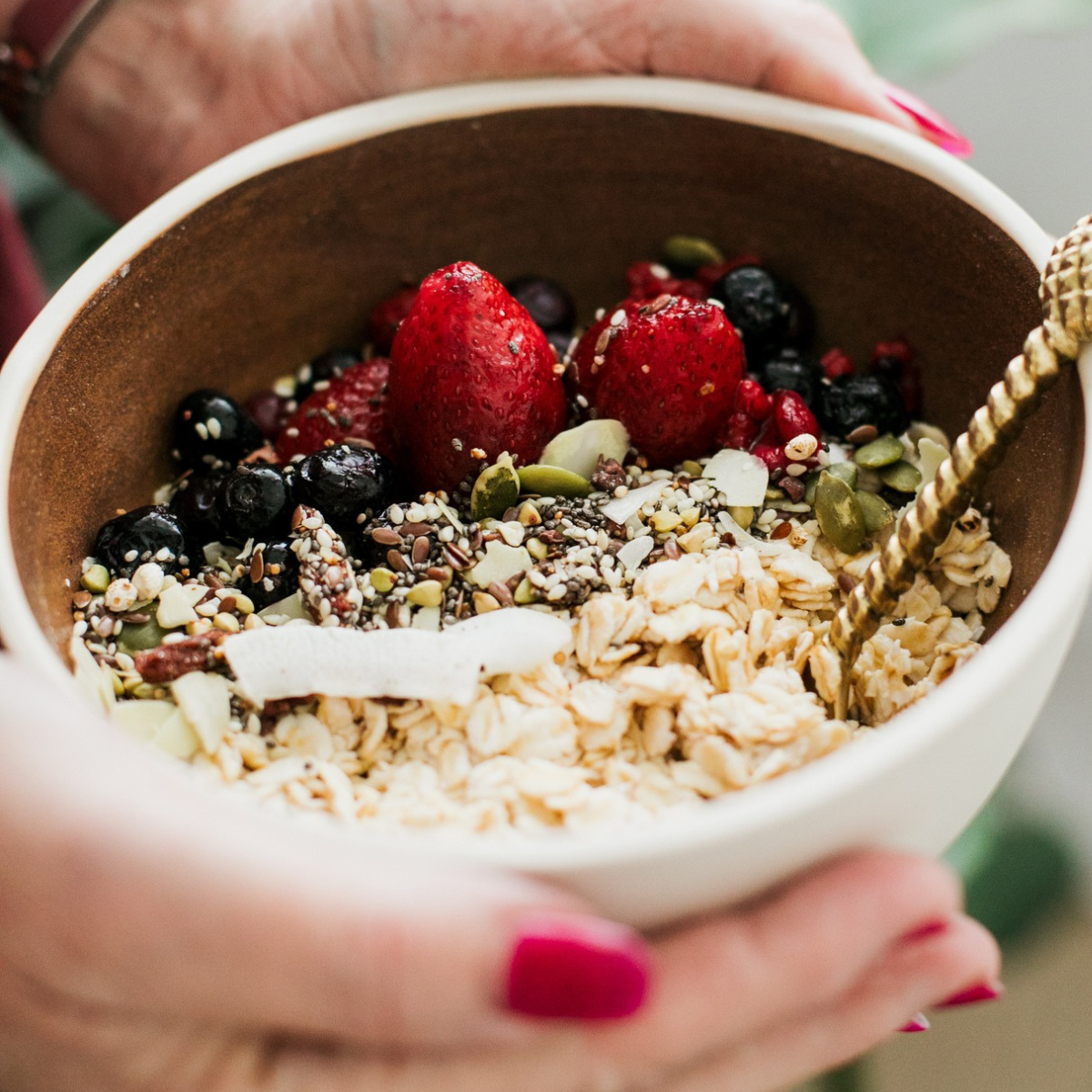Person holding a bowl of a goodMix Blend11 with muesli, berries and seeds.
