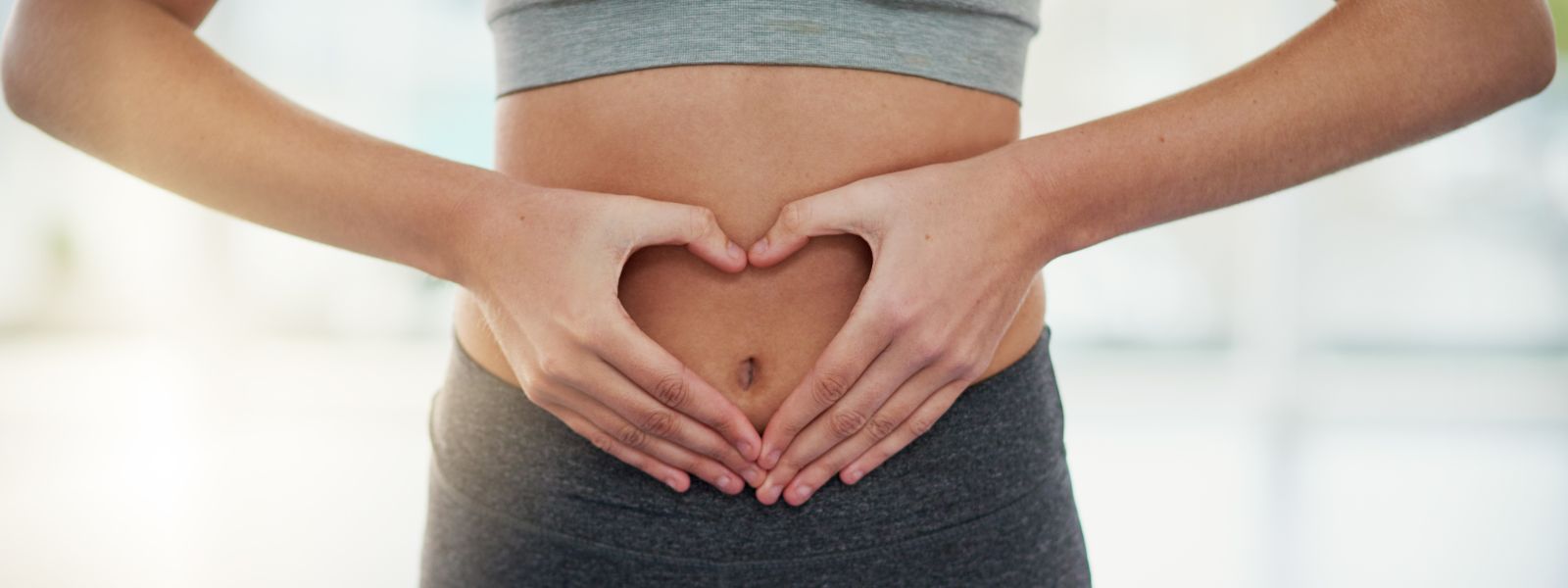 female body using hands to make heart over the gut