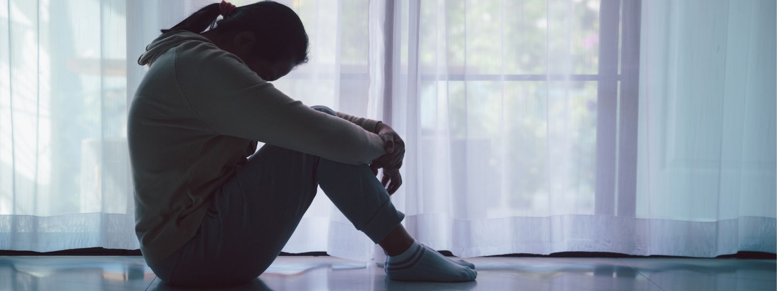 silhouette of a woman sitting on floor looking depressed