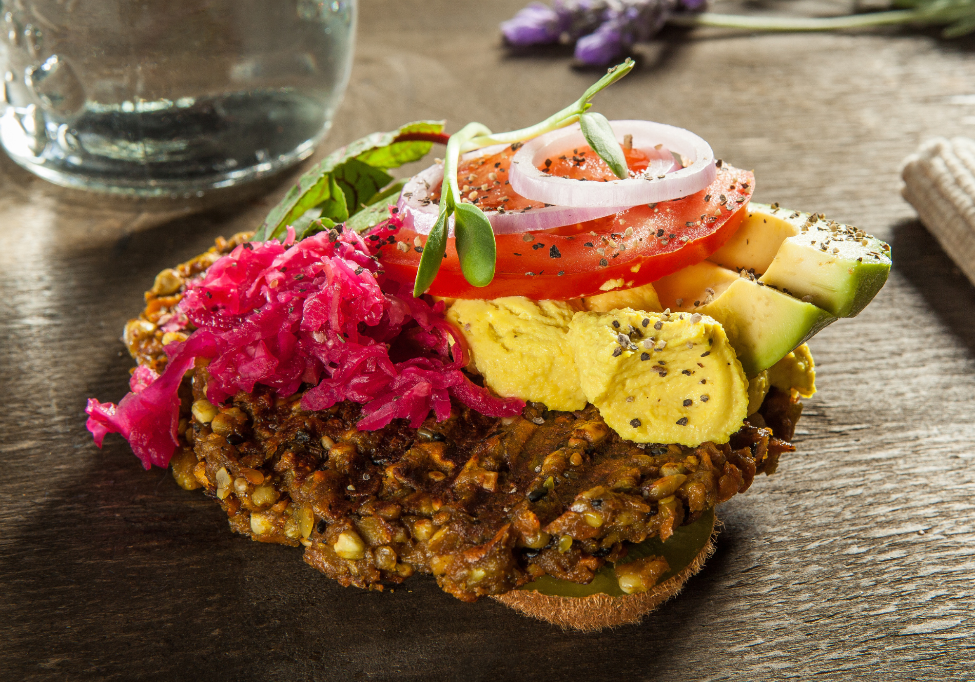 goodMix Burger Mix with avocado, tomato, and pickled onions on a wooden surface.